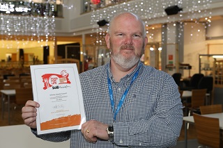 Scott Pring with the Food for Life Served Here Bronze Award certificate. 
