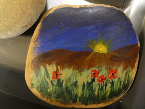 Stone painted with sunset and poppies.