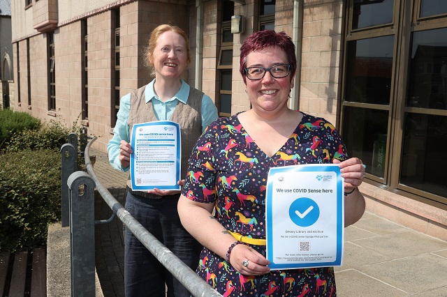 Photo of Orkney Library and Archive team leader Vikki Kerr with COVID Sense signage, and Environmental Health officer Ceri Dare.