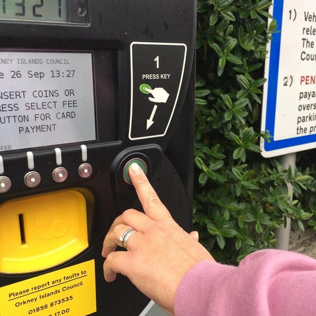 Photo of someone pressing the green button on one of the Council's ticket machines to obtain a valid parking ticket