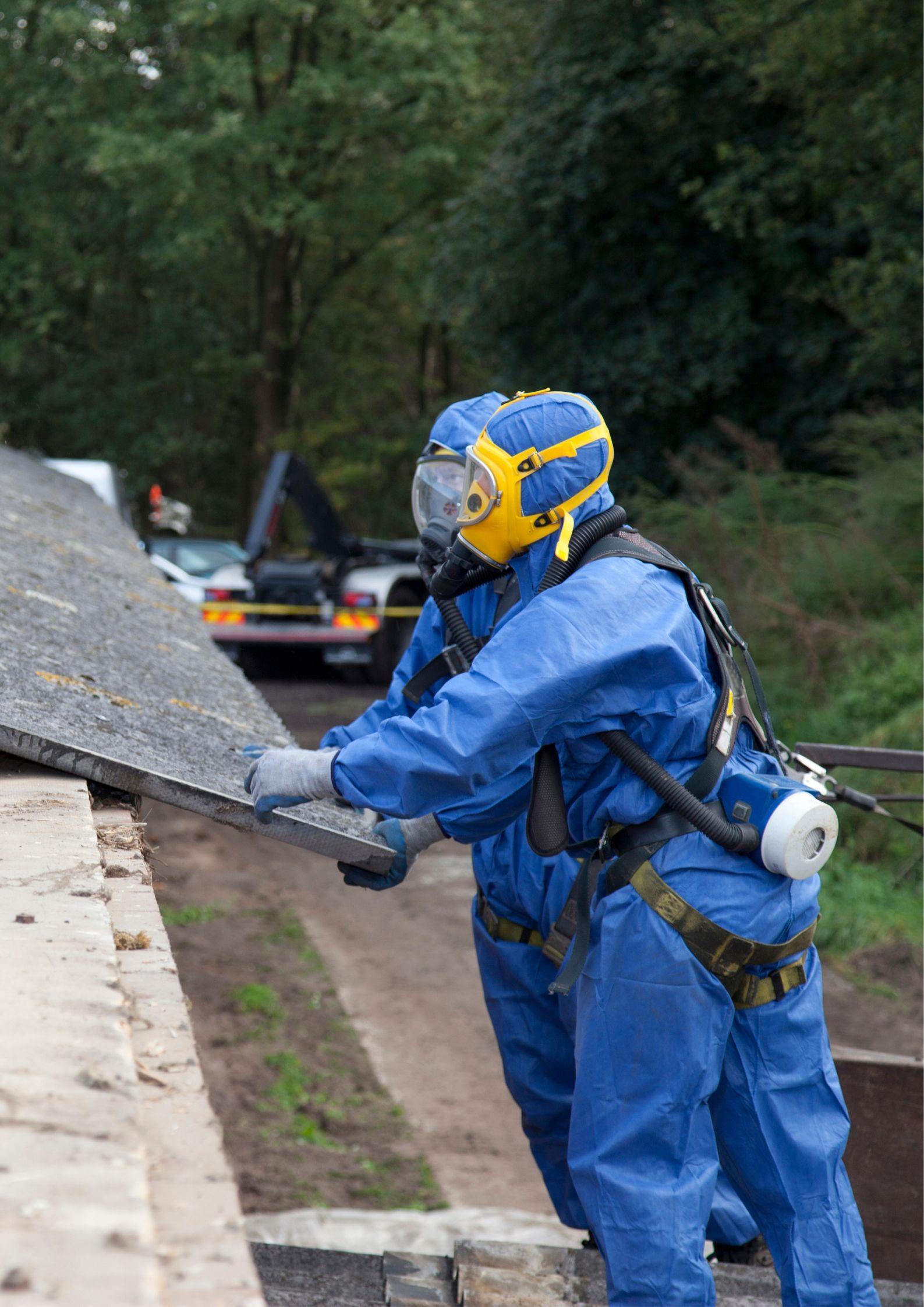 Workers in hazardous suits removing Asbestos sheets.