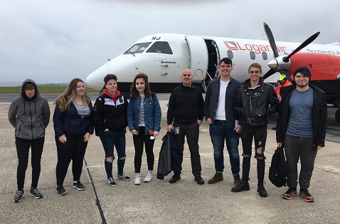 8 people standing beside a Loganair flight