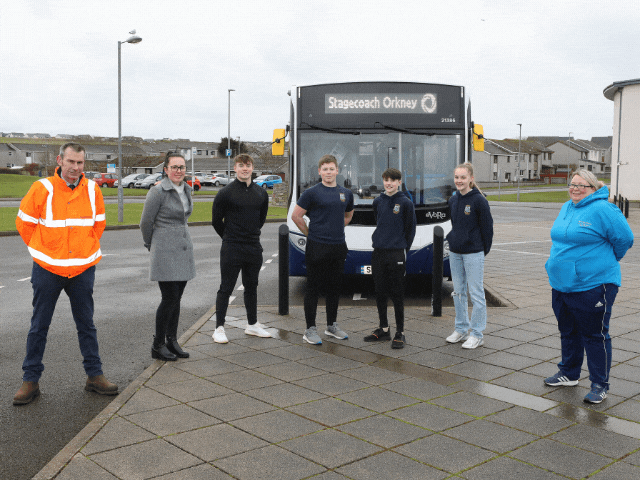 7 people standing in front of a bus