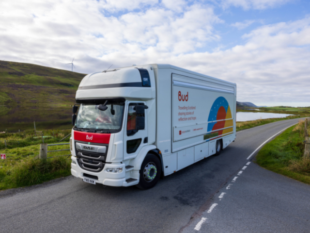 a white van driving down a road with hills around