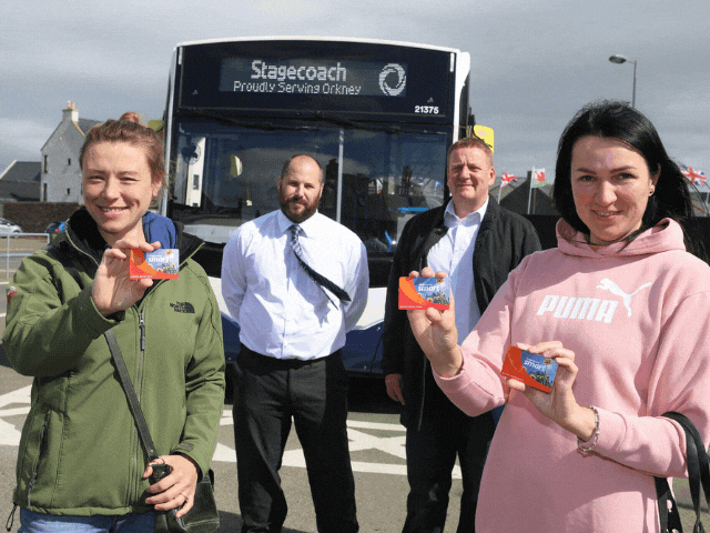 2 women, 2 men, in front of a bus holding bus passes