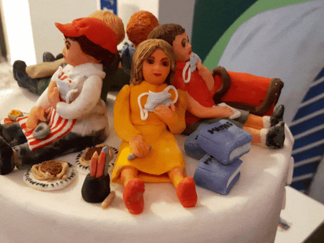 a white cake with 5 icing people on the top