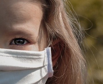 a small child, only one eye visible in photo with mask over her mouth