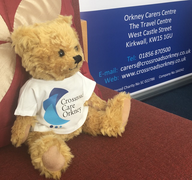 a teddy bear with a Crossroads Care Orkney t-shirt on