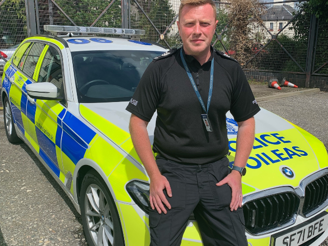 a policeman standing in front of a police car