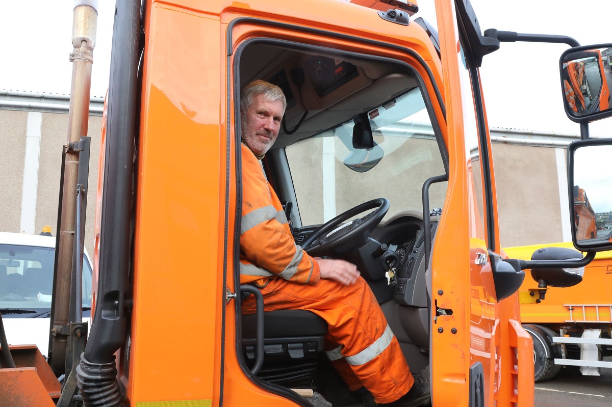 A man in his work overalls sitting in a van