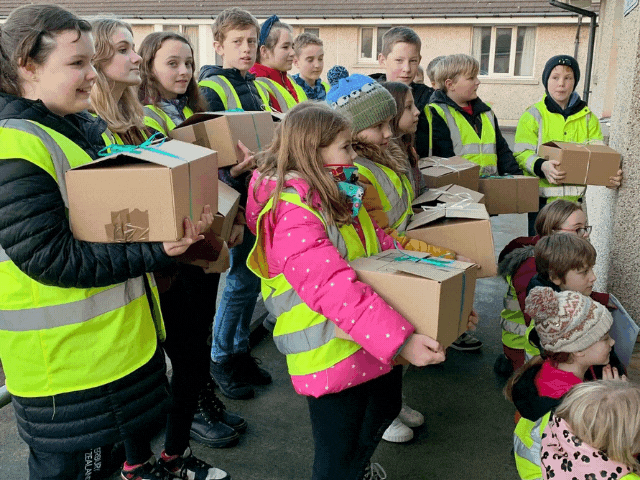 Lots of children delivering boxes standing in hi-vis