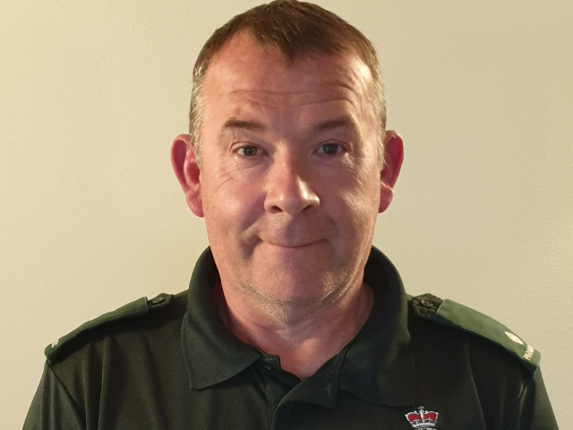 a man smiling at the camera in a Scottish Ambulance t-shirt