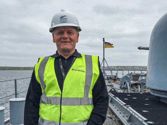 a man standing on a boat with his hi vis on
