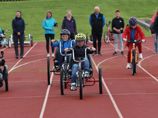 adults and children on a red track cycling