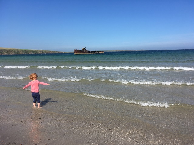 a little girl at a beach with her hands in the air