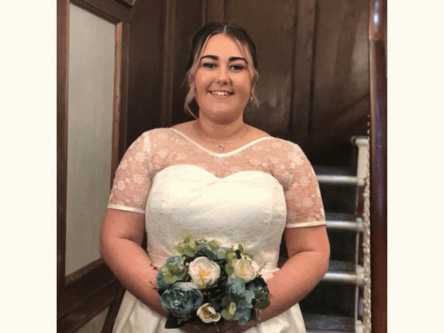 a lady in a wedding dress holding flowers