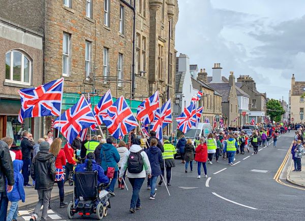 people marching with united kingdom flags down the street