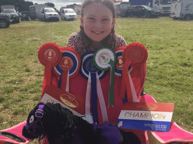 a young girl with lots of rosettes for her horse