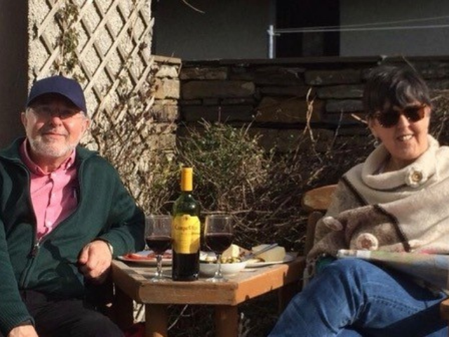A man and lady sitting outside drinking wine in the sun