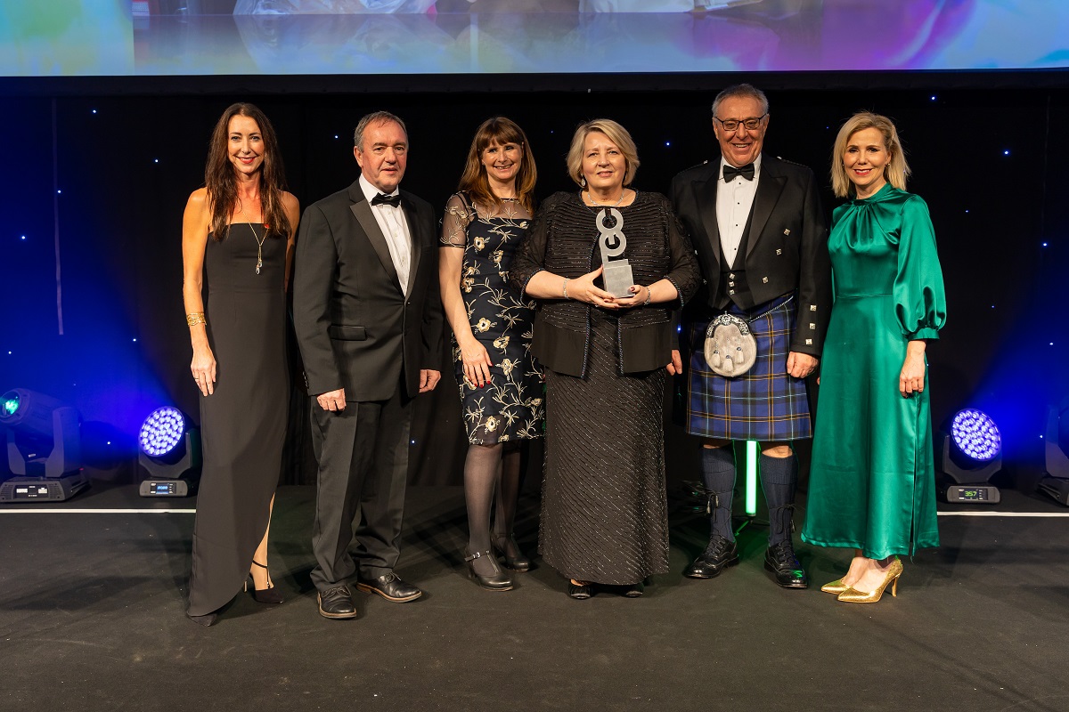 4 women, 2 men standing receiving an award