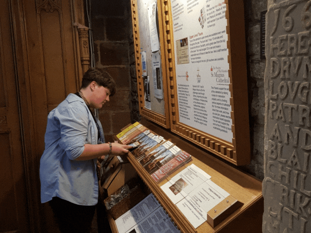 a woman reading a booklet in the St Magnus Cathedral