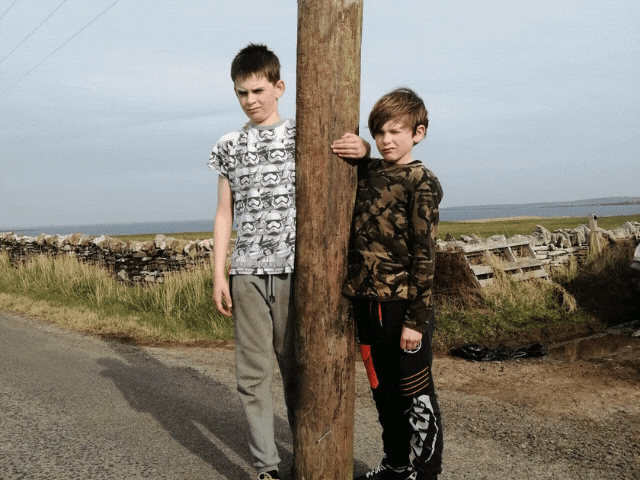 2 boys standing holding a log twice the size of them