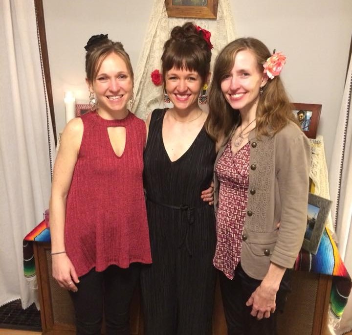 3 ladies standing with flowers in their hair