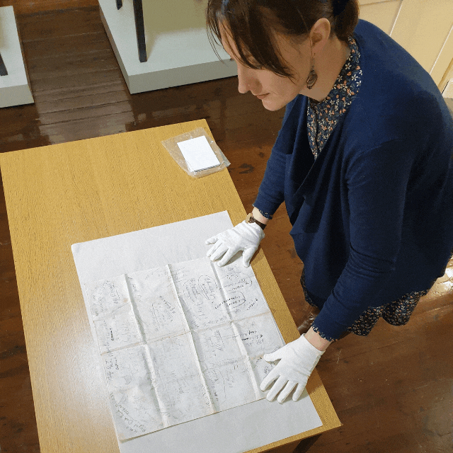 a lady inspecting objects on a table with white gloves on