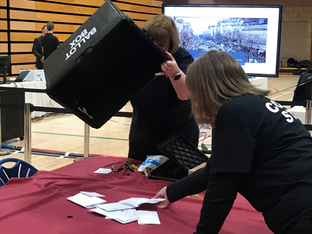 a lady tipping a ballot box out onto a table