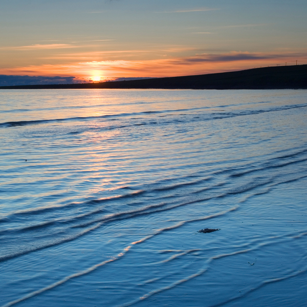 sun setting with water in foreground