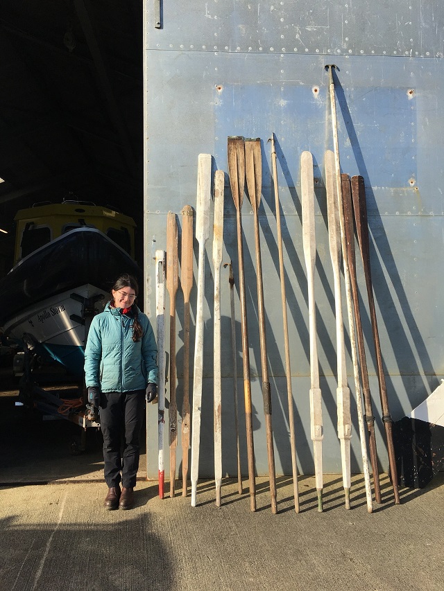 a lady standing beside boat oars