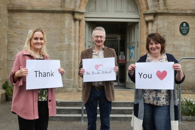 3 people standing in front of the council offices with signs saying thank you