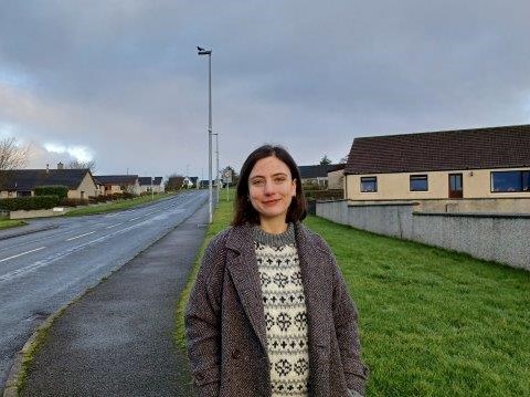 a lady standing at the side of a road