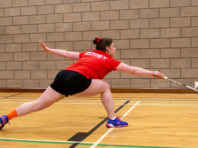 a young adult playing badminton