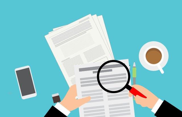 a phone, some paper, cup of tea and a magnifying glass