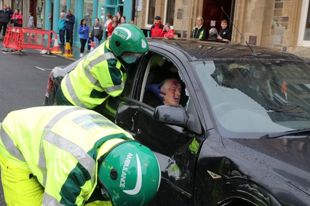 2 members of a fire crew tackling getting someone out of a crashed vehicle in a demonstration