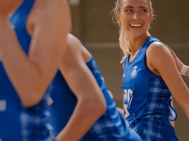 a netballer playing GS smiling at camera wearing a blue netball outfit
