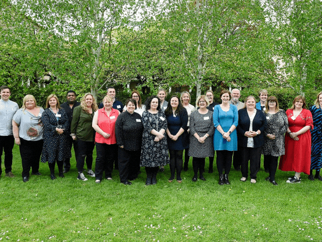 group of people standing in front of a tree