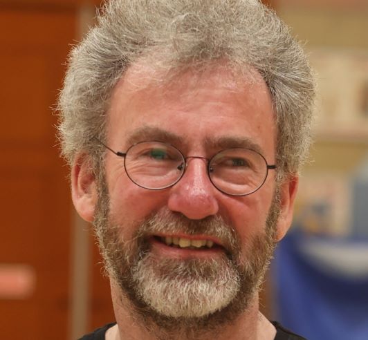 a photo of a man with glasses smiling at the camera