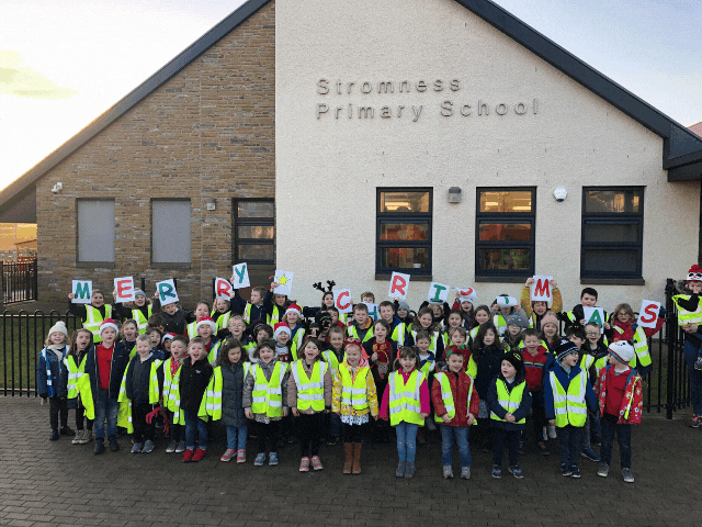 children standing in front of a school in their hi-vis