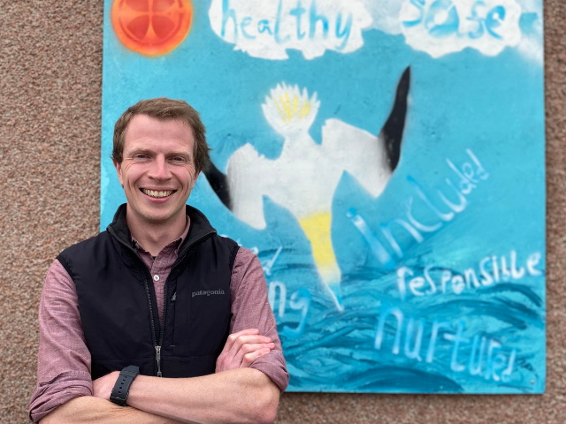a man standing beside a painting with a bird on it