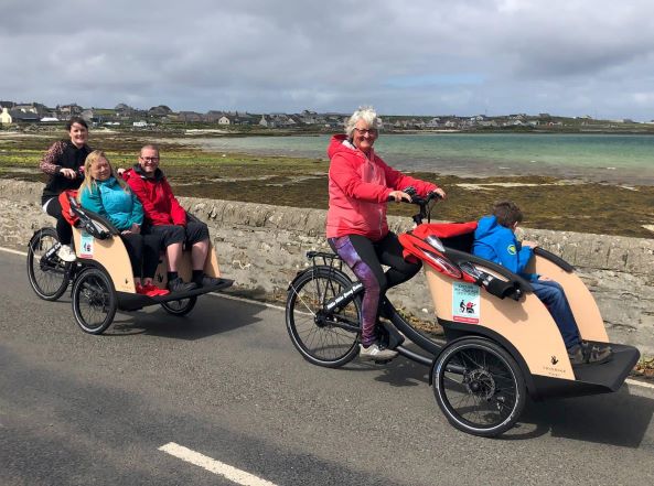 2 people cycling on a tri bike with 3 passengers