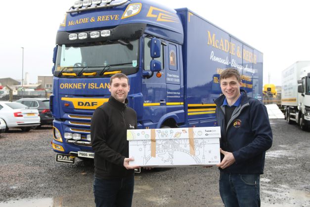 2 men holding a box in front of a Mcadie and Reeves van