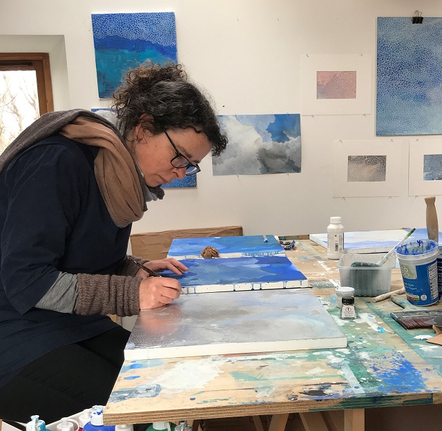 a lady bending over a table painting