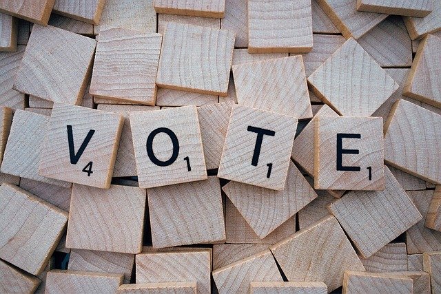 wooden tiles with letters on it spelling vote