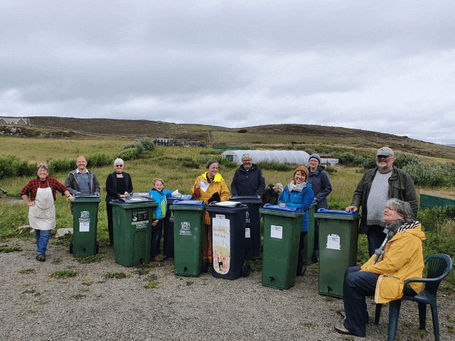10 people standing around plastic bins