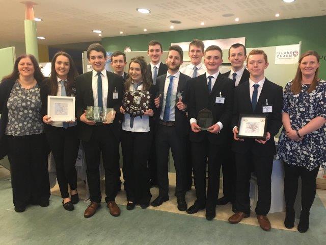 adults and children standing holding trophies and certificates